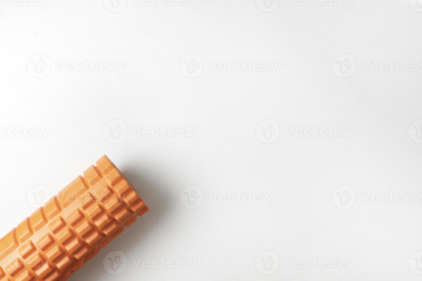 Un rouleau de libération myofascial orange allongé sur un fond blanc photo