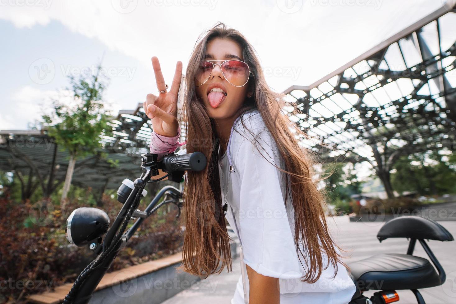 belle jeune femme assise sur un scooter électrique et montrant la langue photo
