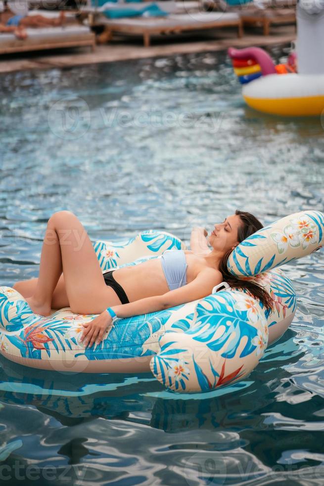 femme sur flamant gonflable flottant dans la piscine. photo