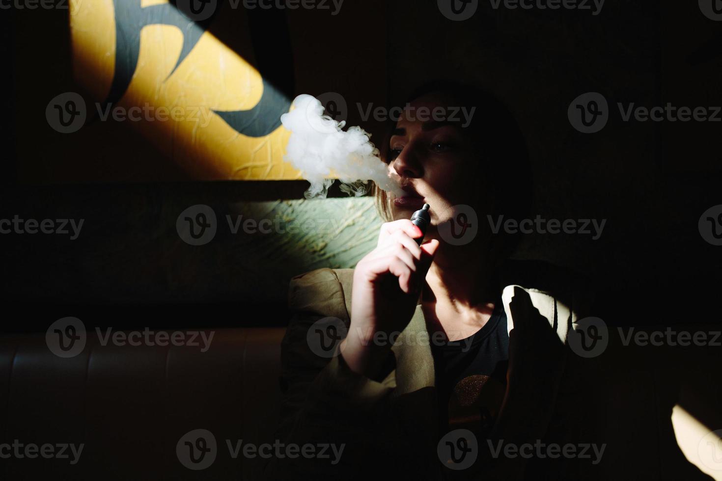 la fille s'assied et fume la cigarette électronique photo