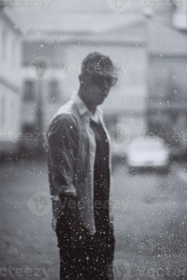 portrait d'un beau jeune homme insouciant se sent libre sous la pluie photo
