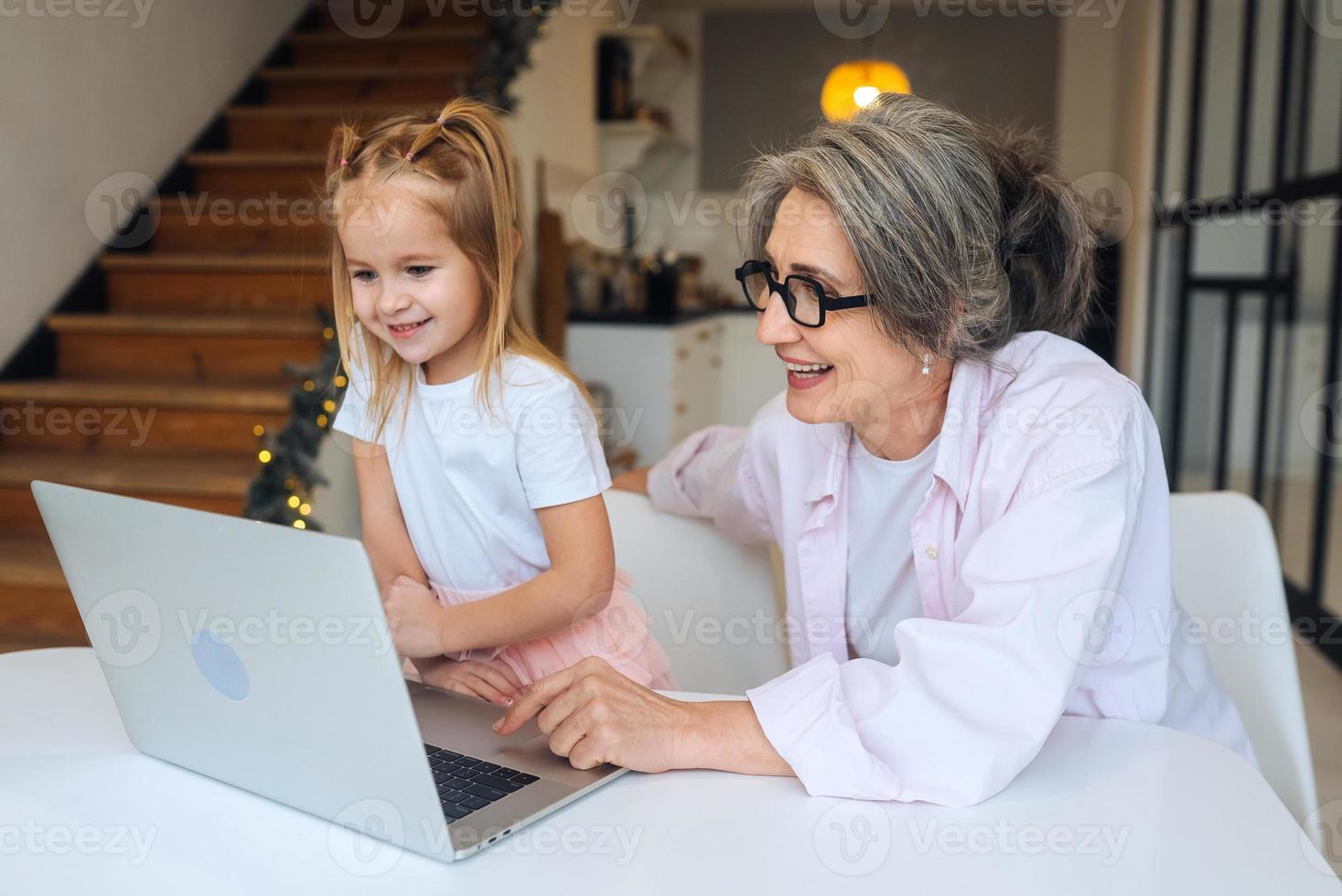 enfant et grand-mère regardant la caméra avec un ordinateur portable photo
