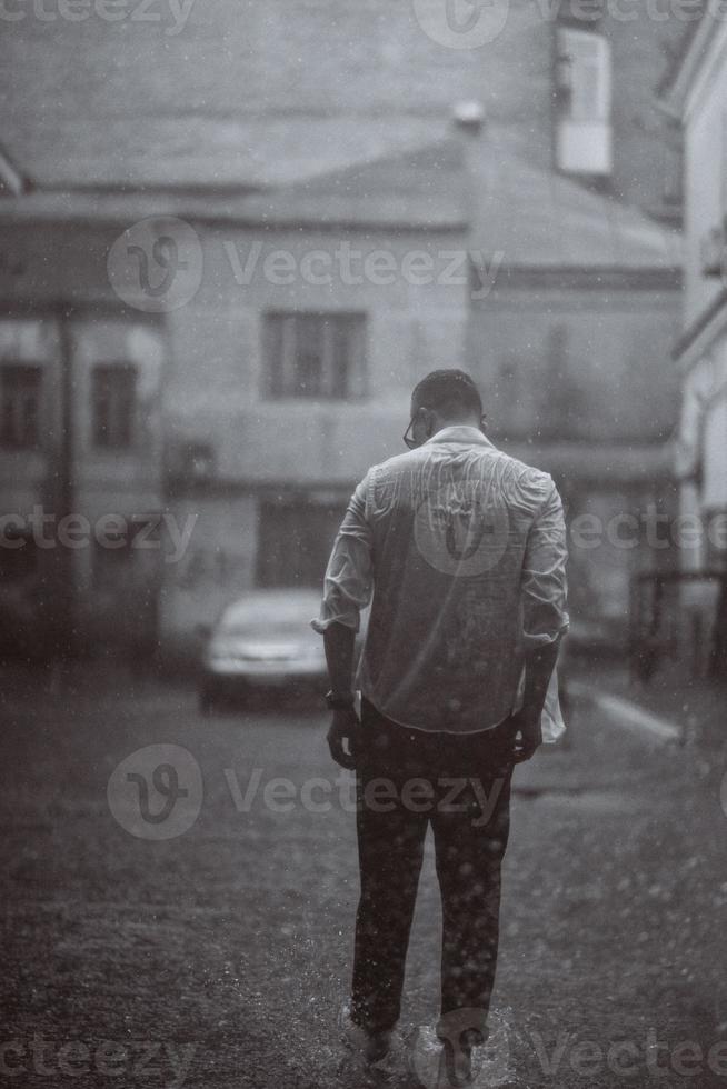 portrait d'un beau jeune homme insouciant se sent libre sous la pluie photo