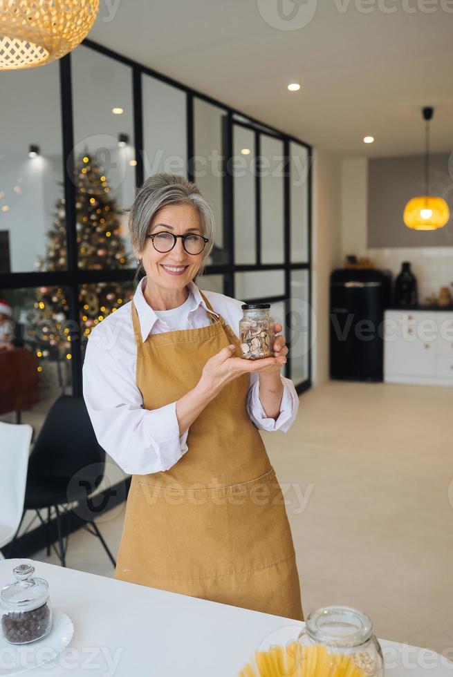 une femme âgée tient un bocal en verre avec des céréales dans ses mains. photo