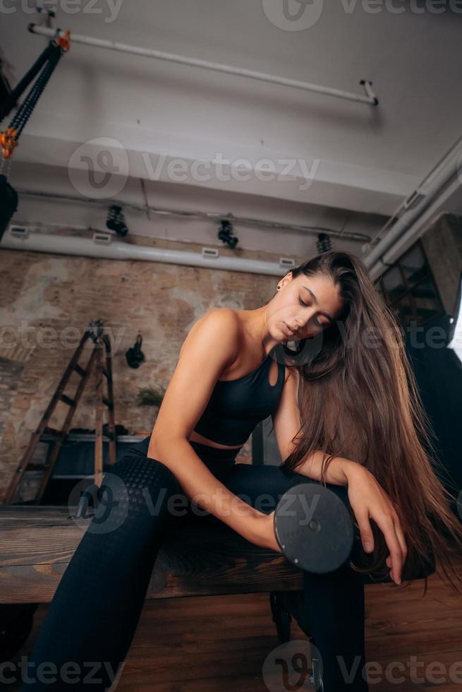 la jeune femme gonfle les muscles en soulevant un haltère par un bras. photo