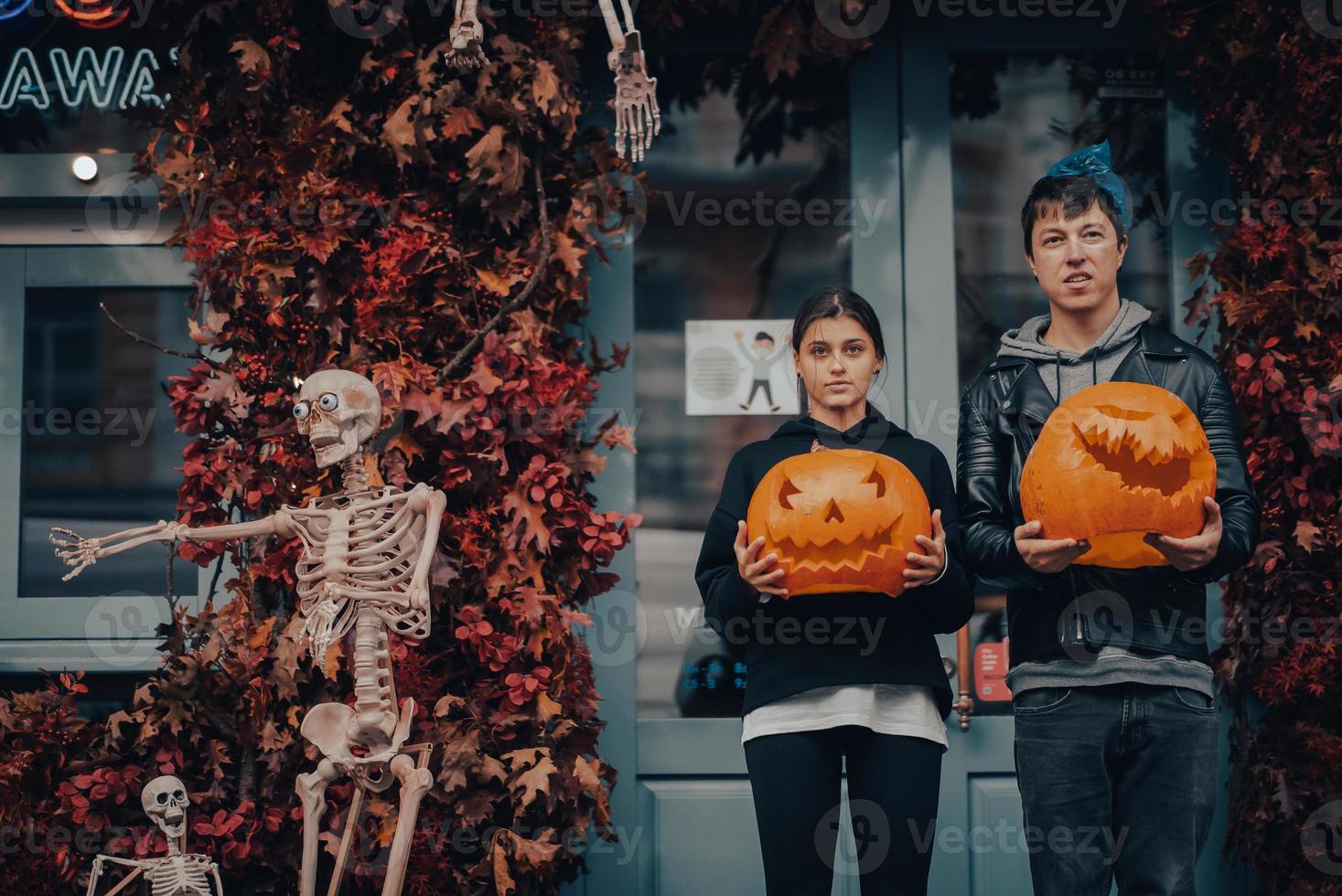 couple tenant des têtes de citrouille près de la porte dans la rue photo