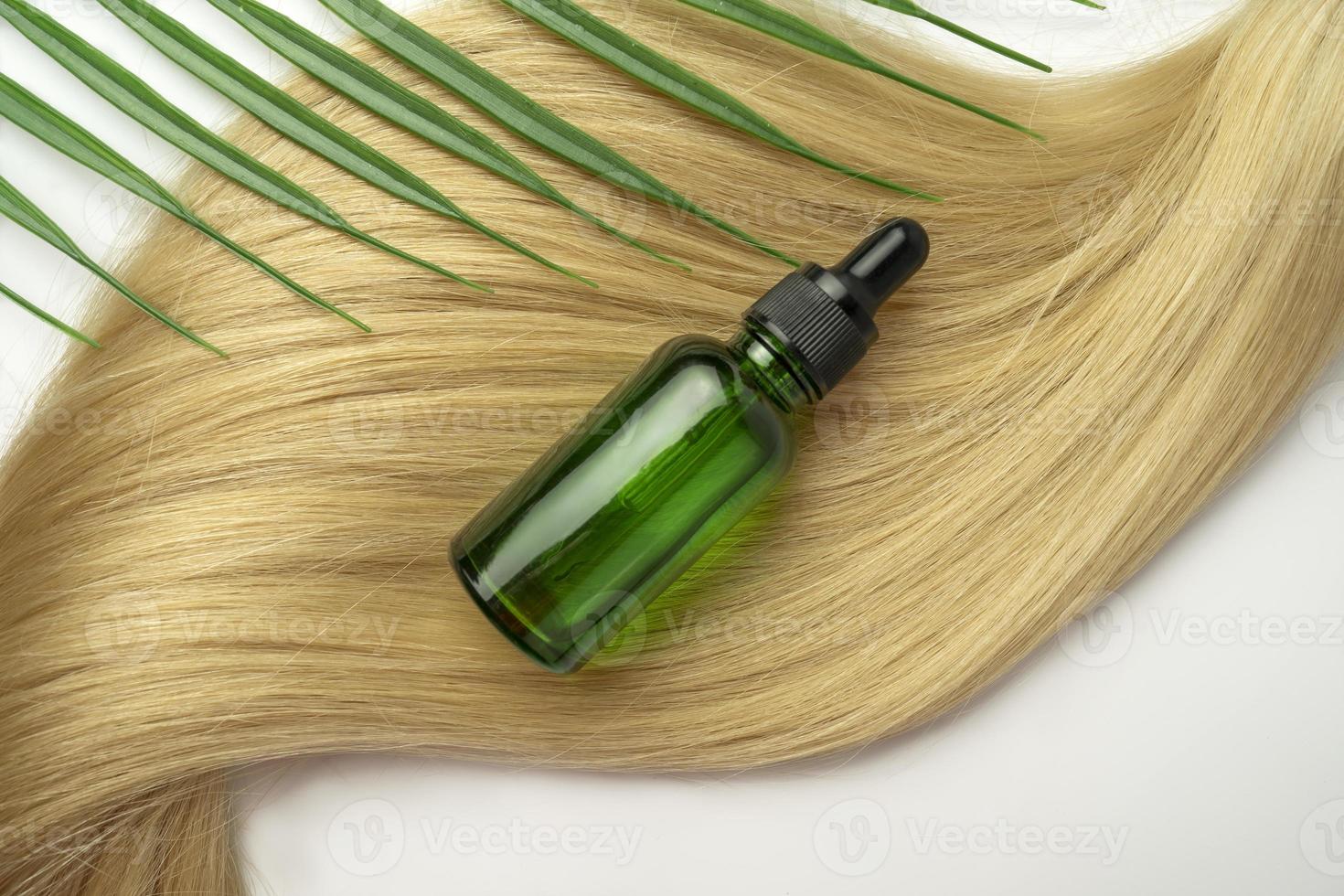 une huile ou un sérum naturel pour le soin des cheveux posé sur une nappe de cheveux blonds photo