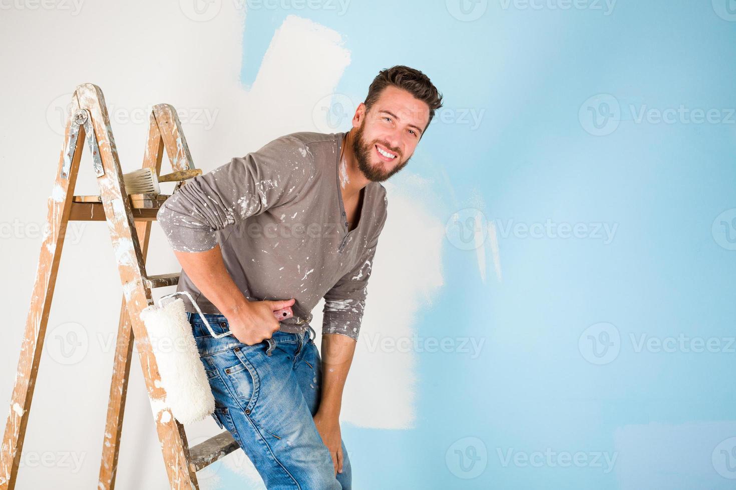 peintre en peinture éclaboussé chemise peignant un mur photo