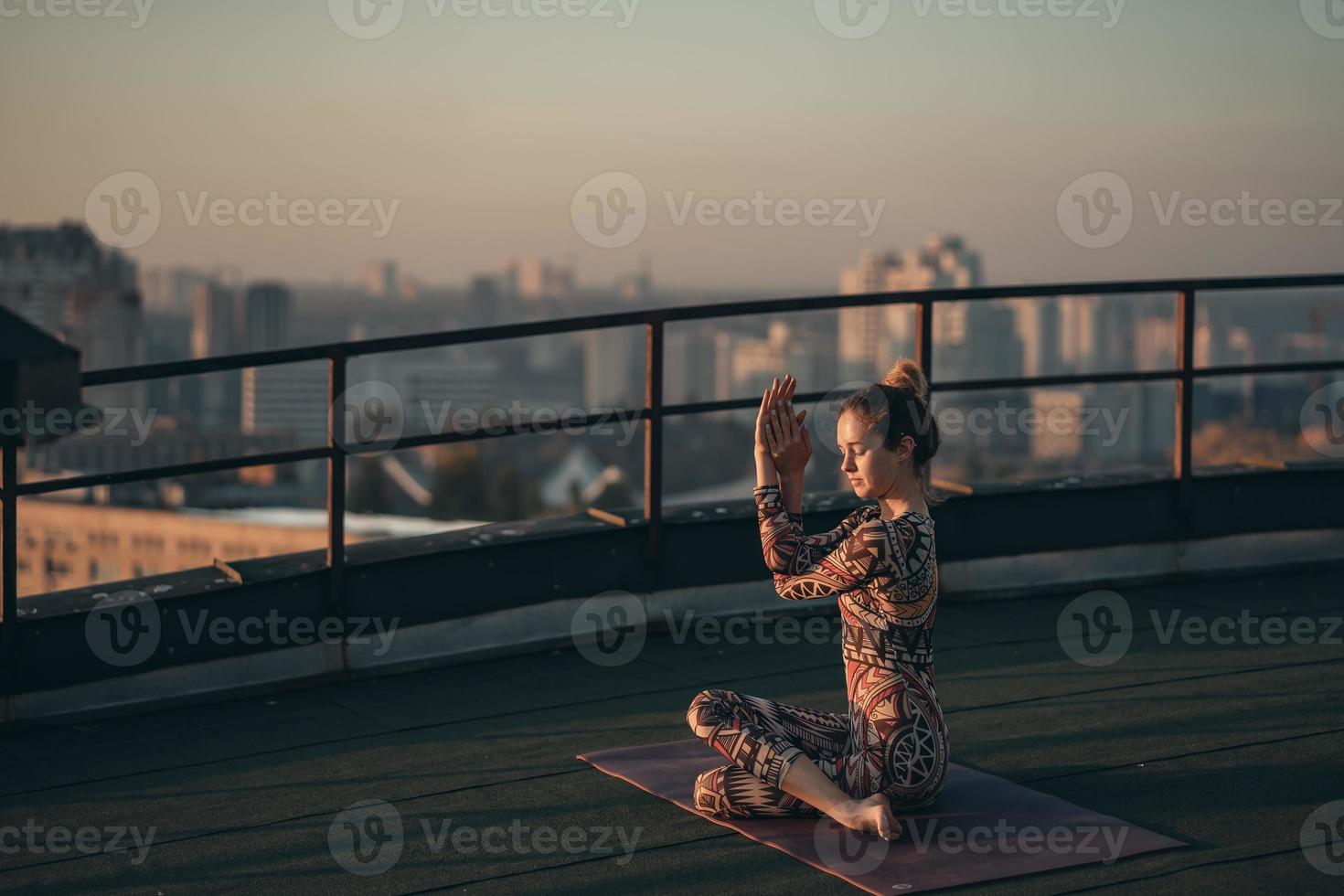 femme faisant du yoga sur le toit d'un gratte-ciel dans une grande ville. photo