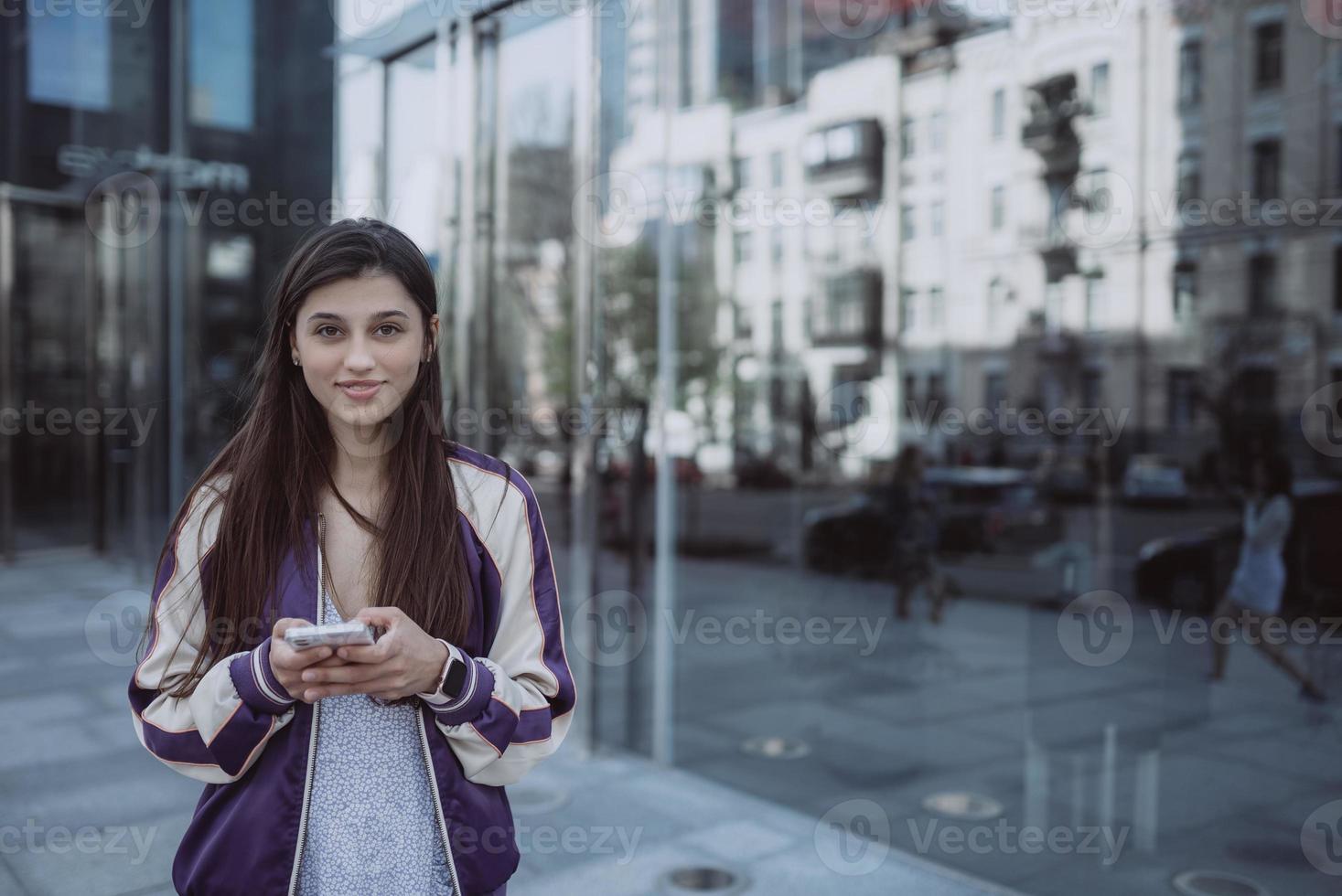 femme heureuse dans la rue à l'aide d'un smartphone et regardant la caméra photo