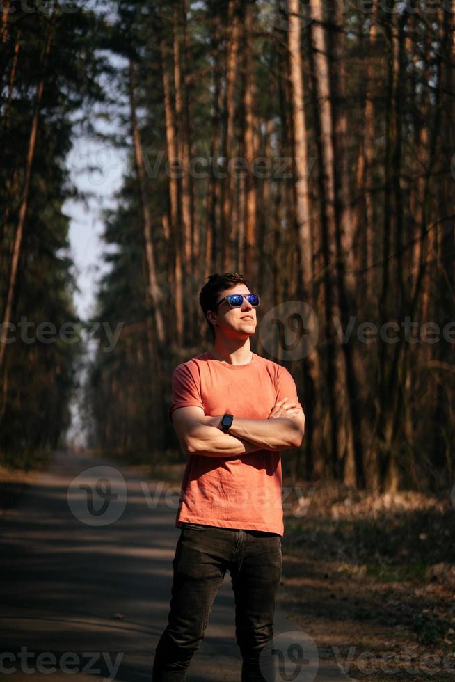 beau jeune homme en t-shirt blanc et jeans en plein air dans le parc, marchant dans le parc photo