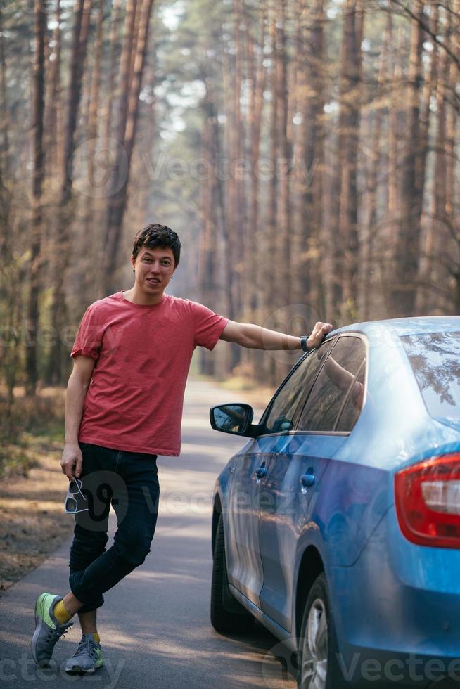 bel homme debout sur la route près de la porte ouverte de sa voiture. photo