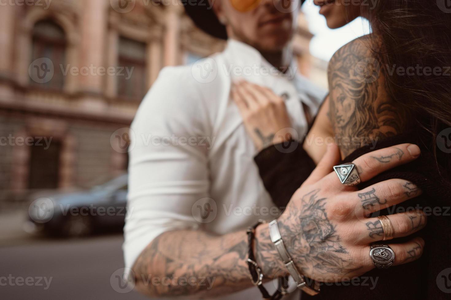 la main de l'homme dans les tatouages et les bijoux embrasse la taille d'une fille. photo