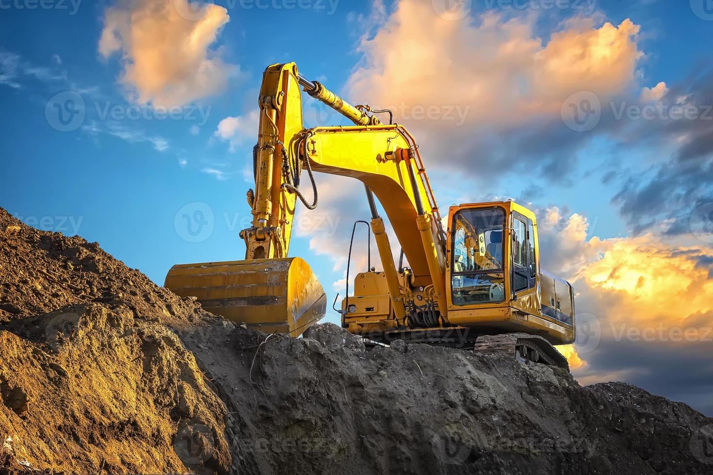 une excavatrice jaune s'arrêtant à un coucher de soleil incroyablement beau photo