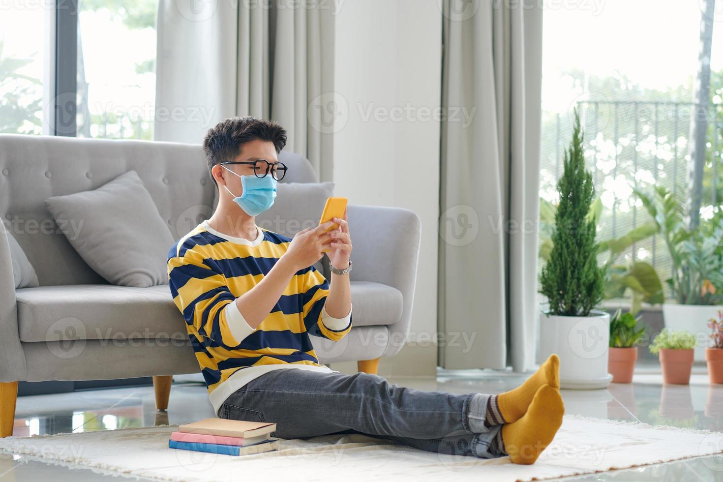 jeune homme portant un masque médical tenant un téléphone portable et des cartes de crédit dans les mains photo