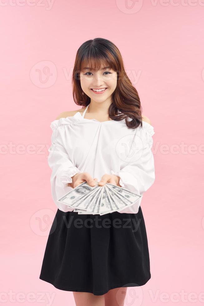 photo d'une jeune fille rêvant heureuse isolée sur fond de mur rose tenant de l'argent.