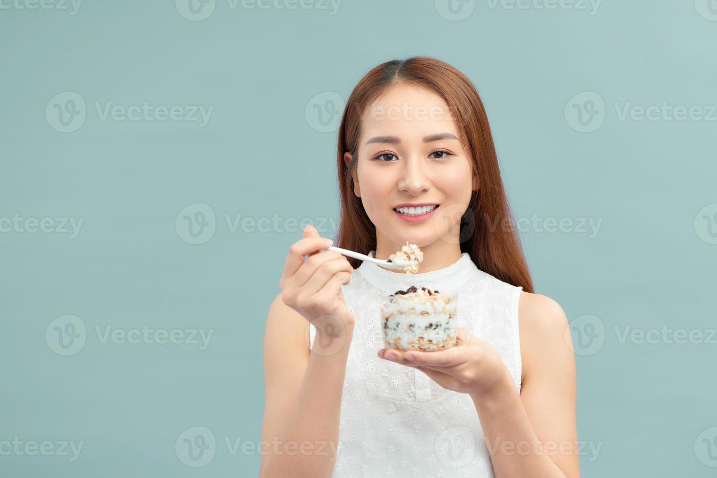 nourriture saine de perte de poids. jeune femme mangeant du yaourt, des raisins secs et des flocons d'avoine photo