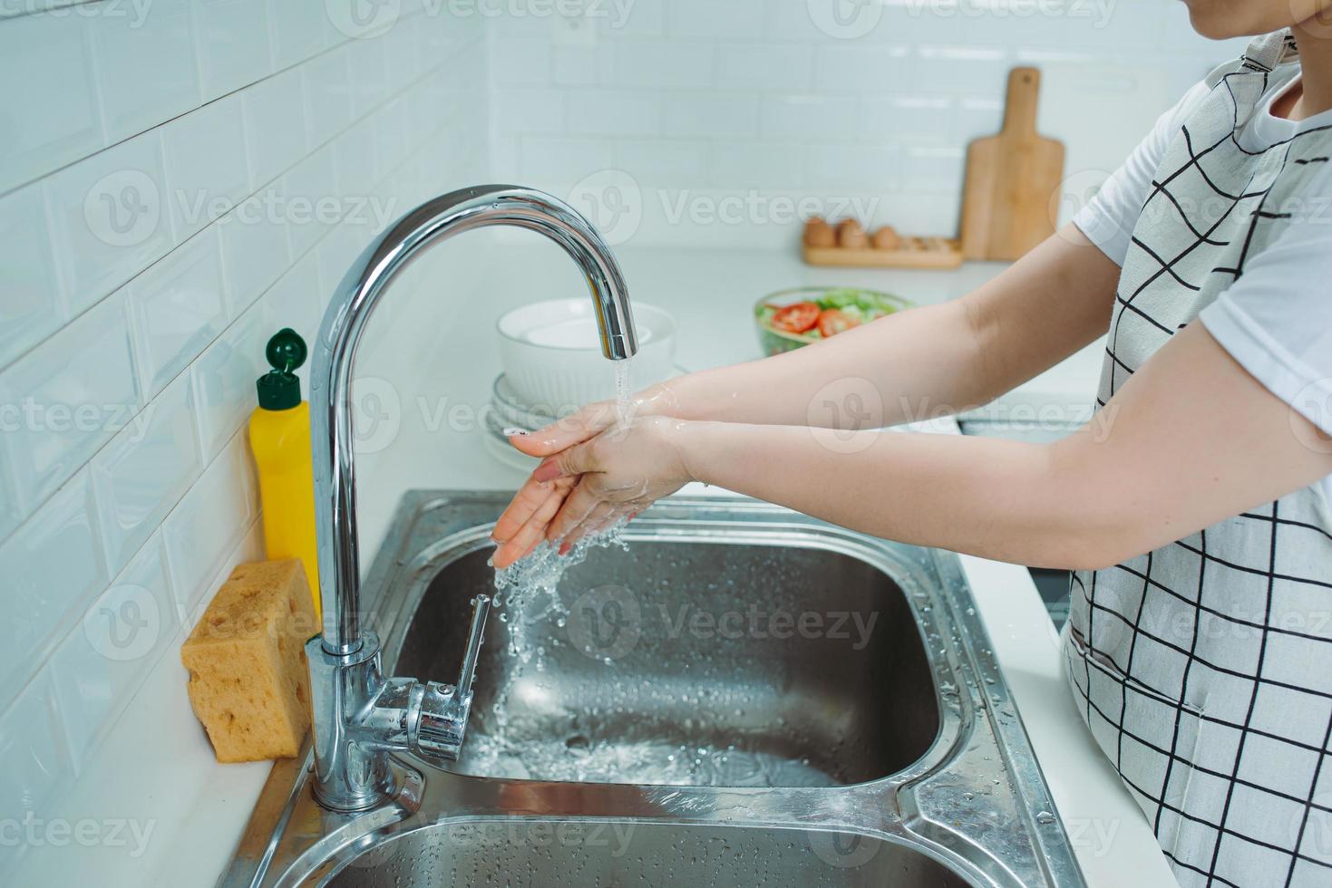 jolie jeune femme fait la vaisselle tout en faisant le ménage à la maison photo