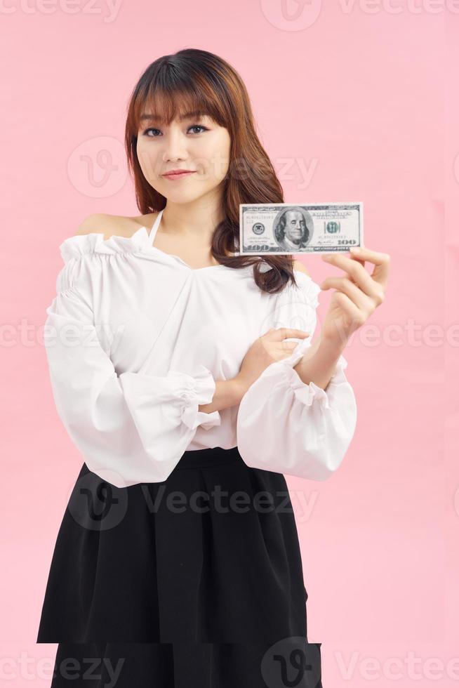 jolie fille souriante regardant la caméra et tenant de l'argent isolé sur blanc photo