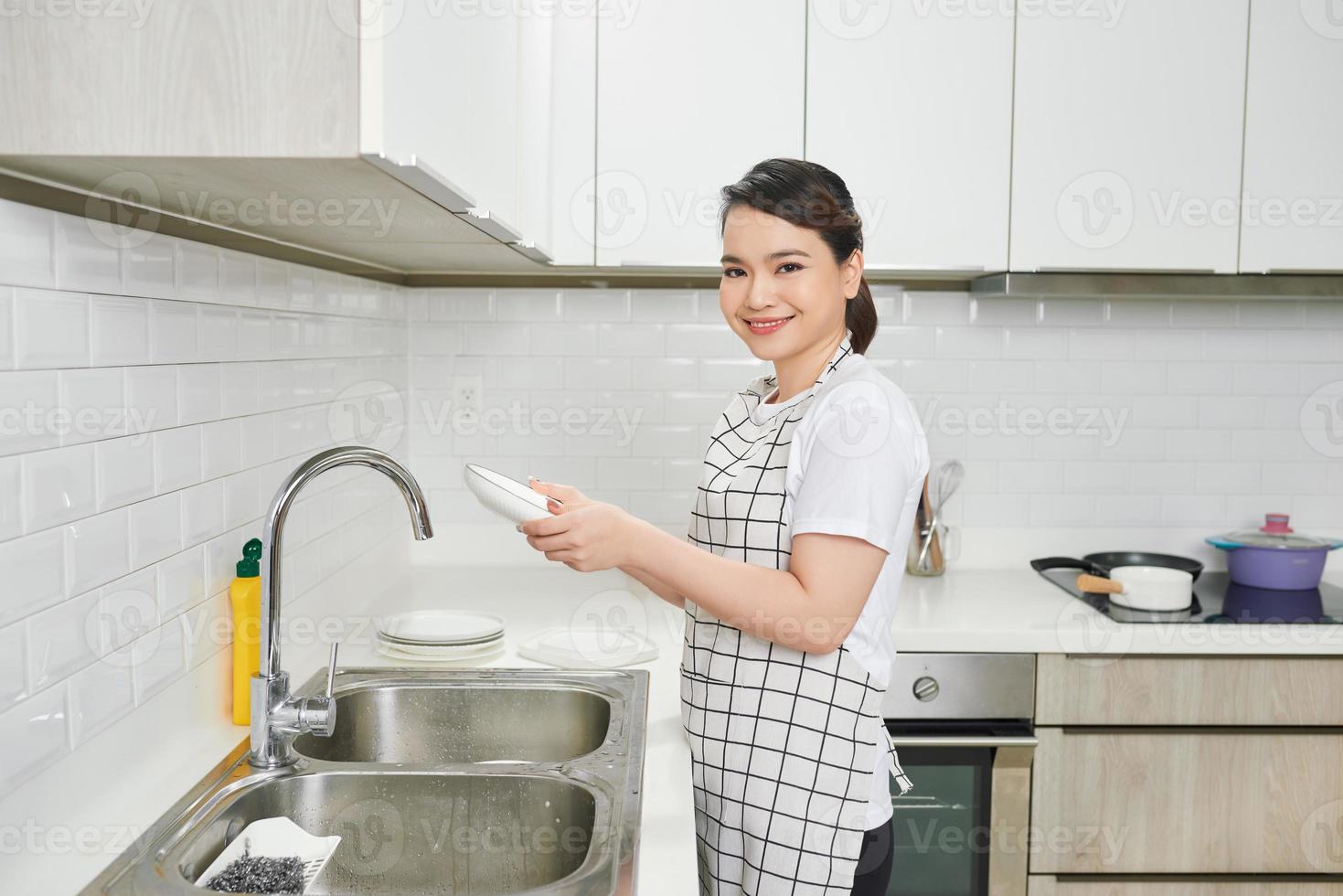 jeune femme a lavé la vaisselle dans une cuisine photo