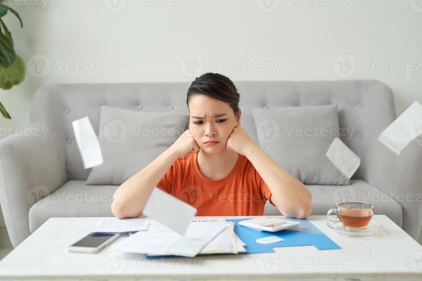 une fille triste et fatiguée de travailler avec des documents et un ordinateur portable, est assise sur un canapé à la maison. travail à distance photo