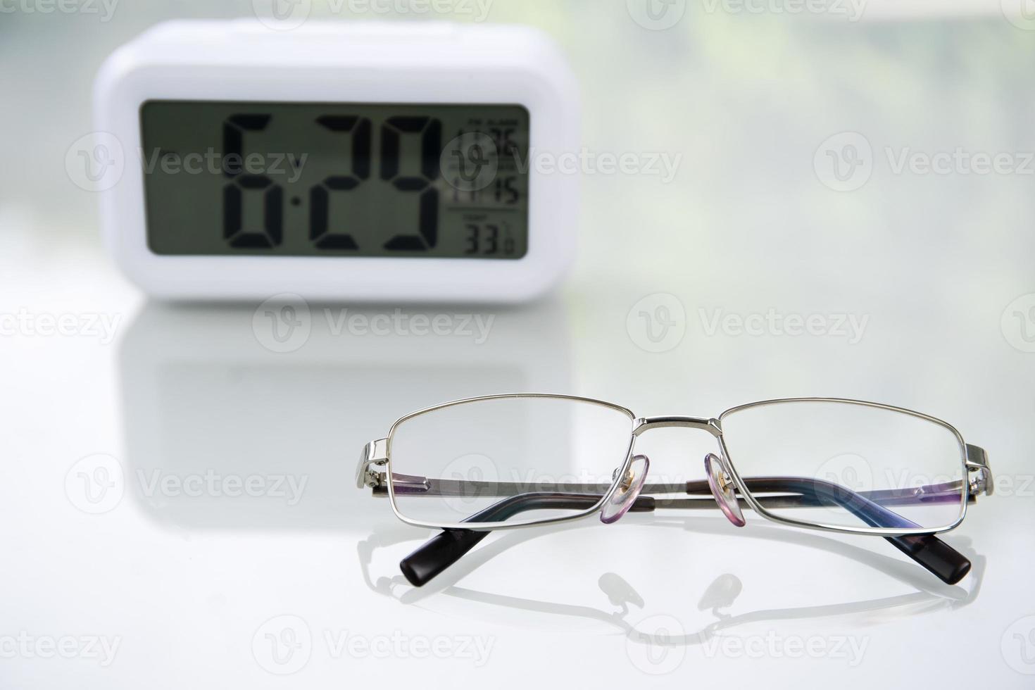 lunettes sur table à la maison avec horloge numérique photo