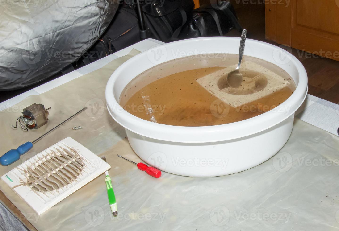 laver les pièces en plastique d'un ventilateur d'extraction de cuisine très sale dans une solution aqueuse d'hydroxyde de sodium photo