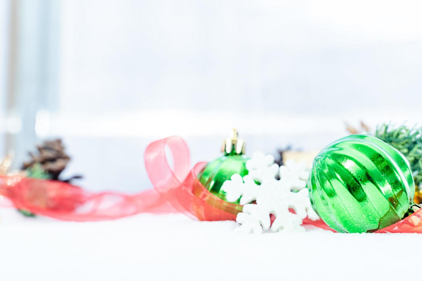 noël d'hiver - boules de noël avec ruban sur la neige, concept de vacances d'hiver. boules vertes de noël, boules dorées, décorations de pins et de flocons de neige sur fond de neige photo