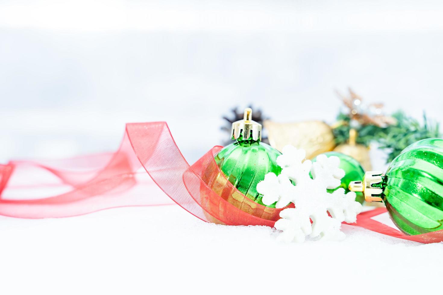 noël d'hiver - boules de noël avec ruban sur la neige, concept de vacances d'hiver. boules vertes de noël, boules dorées, décorations de pins et de flocons de neige sur fond de neige photo