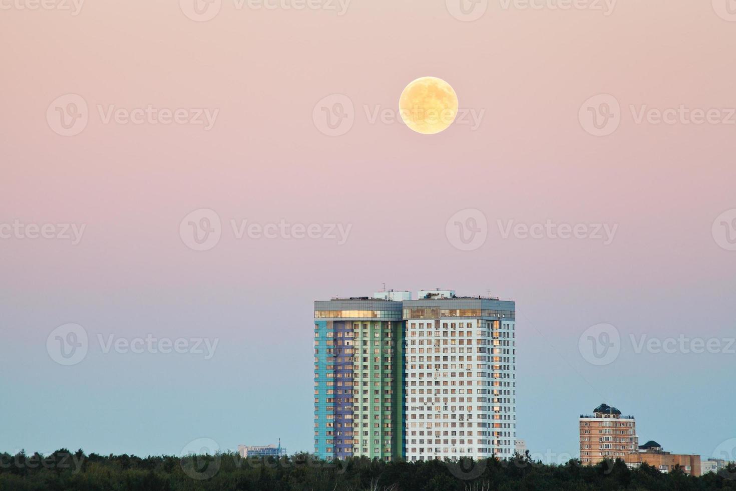 pleine lune dans le ciel rose au-dessus des maisons urbaines photo