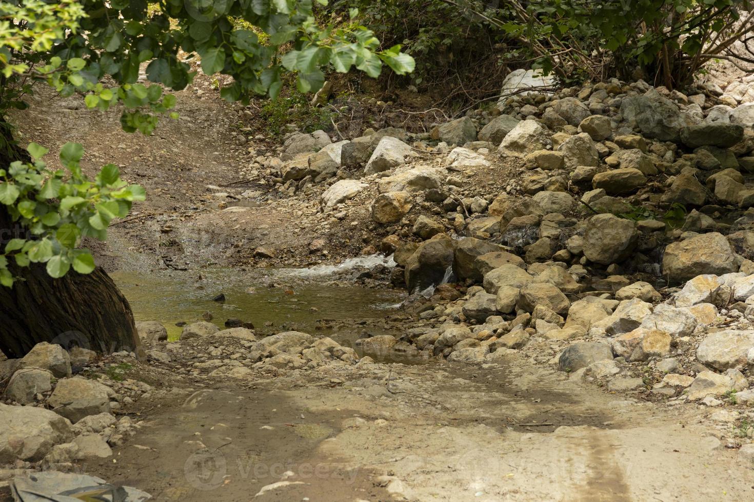 une route de montagne en terre battue et une petite rivière traversant la route. hors route. photo