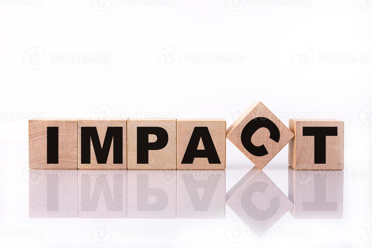 mot d'impact, texte écrit sur des cubes en bois sur fond blanc avec réflexion. photo