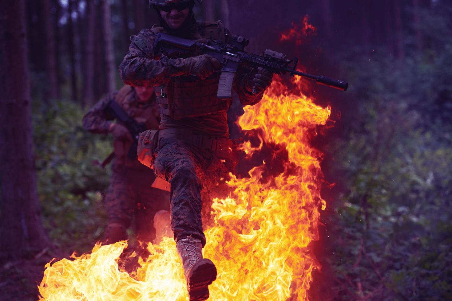 soldat en action la nuit sautant par-dessus le feu photo