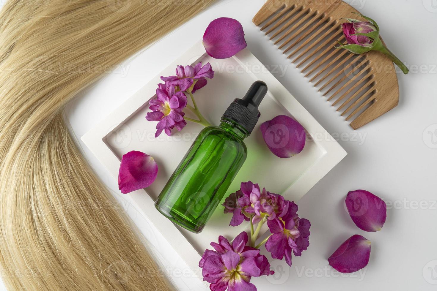 un sérum ou une huile pour le visage vert à base de pétales de rose avec un extrait de fleur se trouvant entre les pétales, une maquette de marketing de produit. un concept de soins capillaires en salon ou à domicile photo