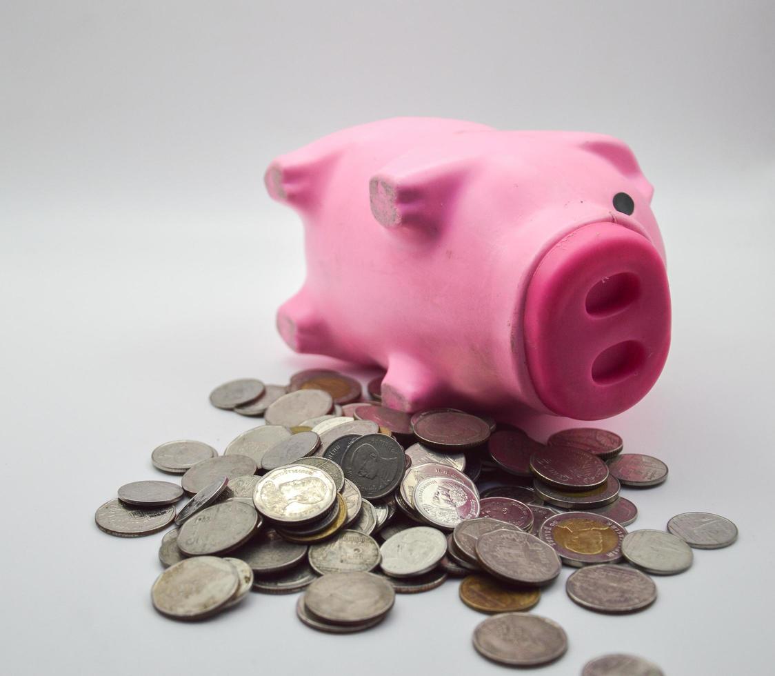 Cochon rose allongé sur un tas de pièces fond blanc concept compte bancaire d'épargne compte bancaire finance économie retraite photo