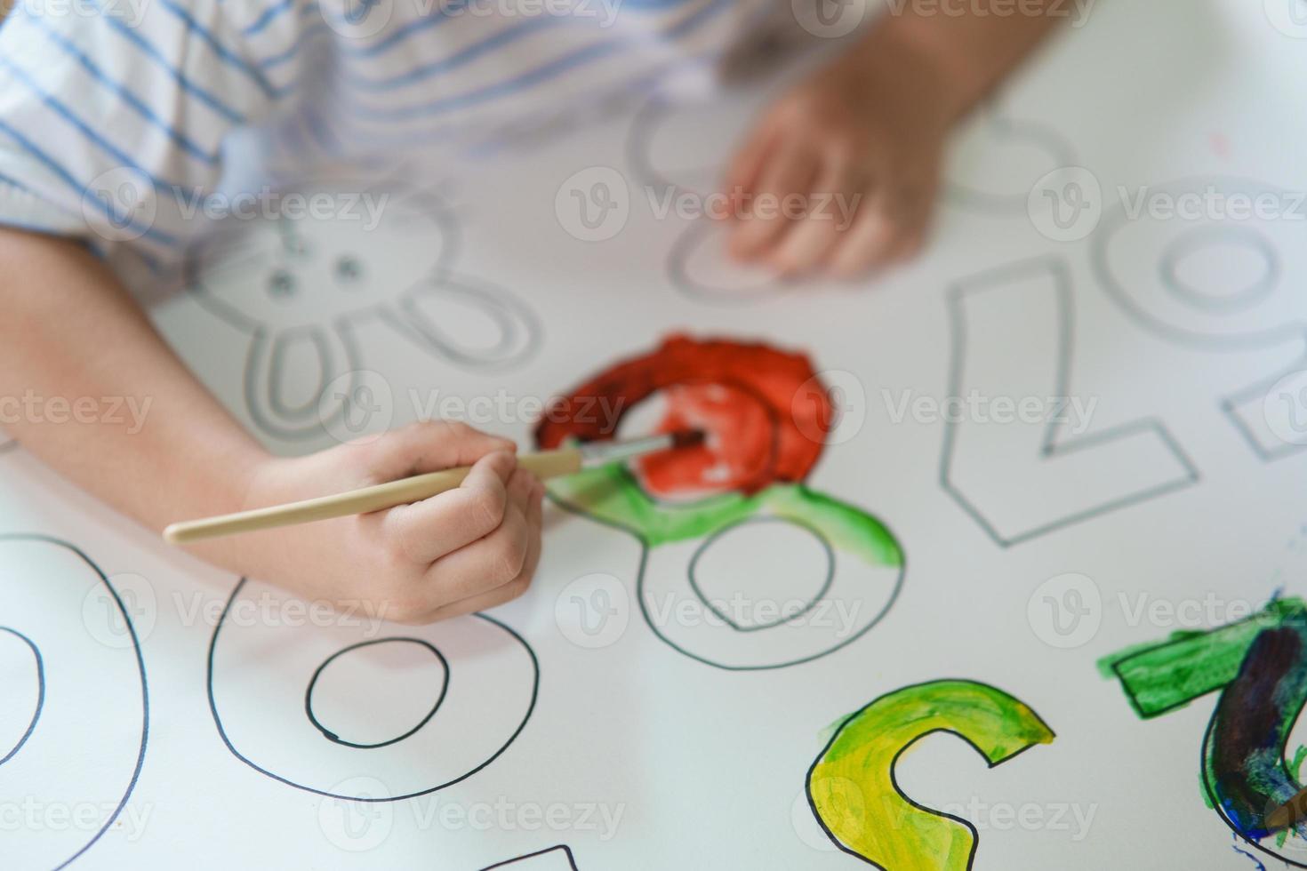 mignon petit bébé asiatique souriant peinture avec des peintures colorées à l'aquarelle. fille asiatique utilisant la couleur de dessin au pinceau. concept de mode de vie d'activité de bébé. photo