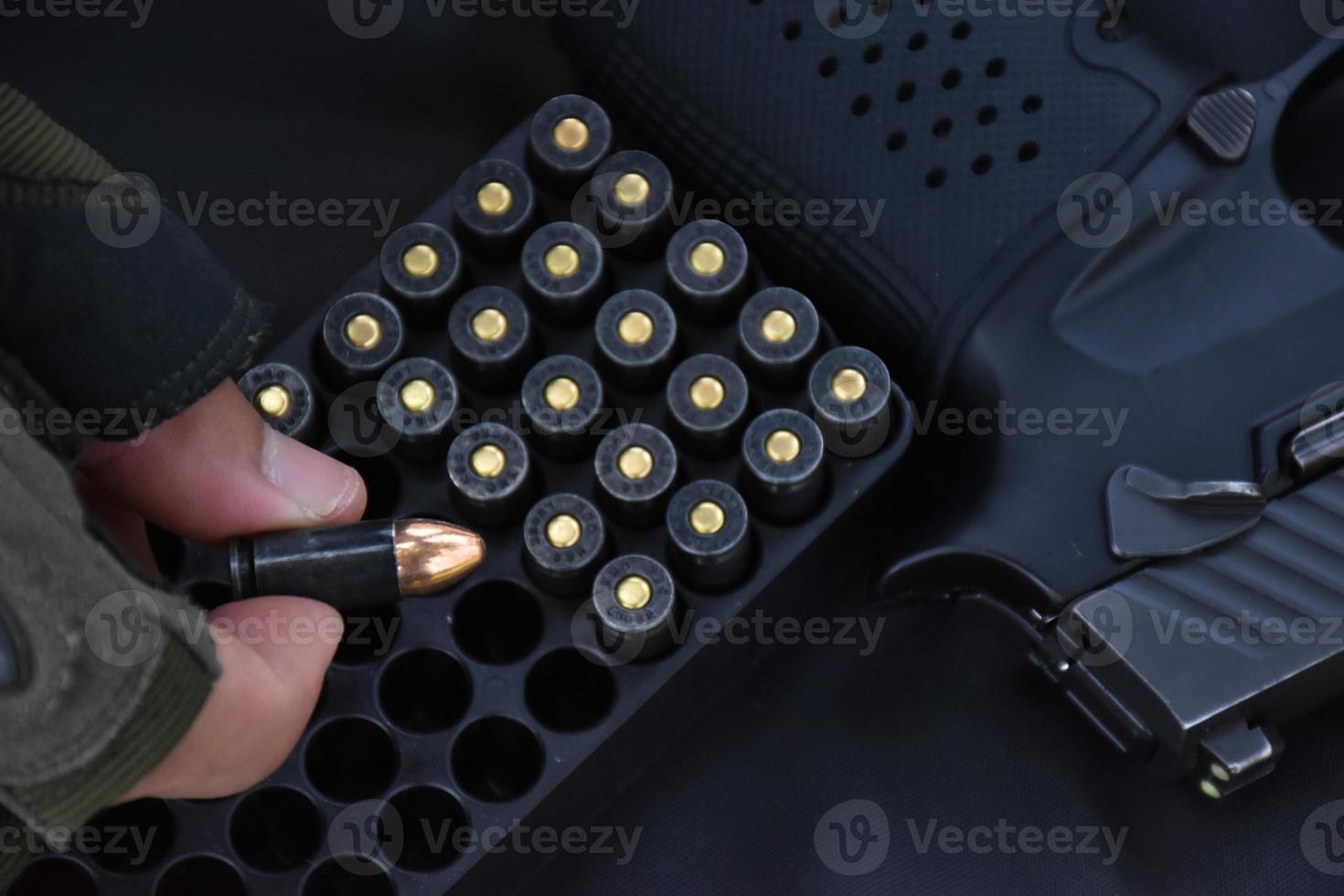 Coquilles de balle de 9 mm tenant dans les doigts et placées près d'un pistolet de 9 mm sur fond de cuir noir, mise au point douce et sélective sur la balle et les doigts. photo