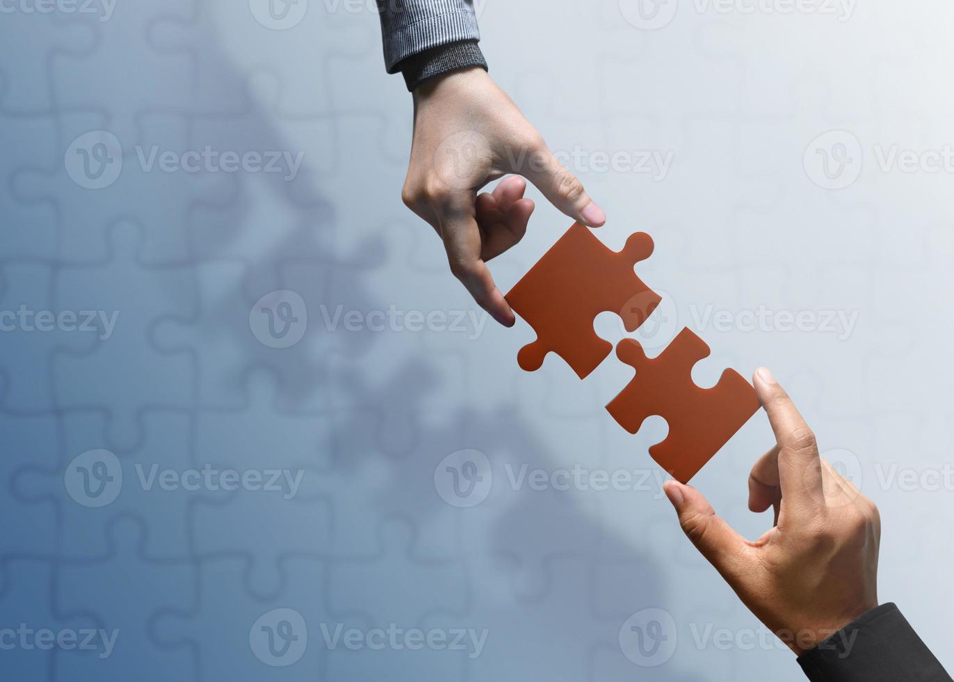 partenariat commercial ou concept de travail d'équipe. les mains de deux personnes essaient d'adapter ou de connecter une pièce de puzzle ensemble. vue de dessus photo