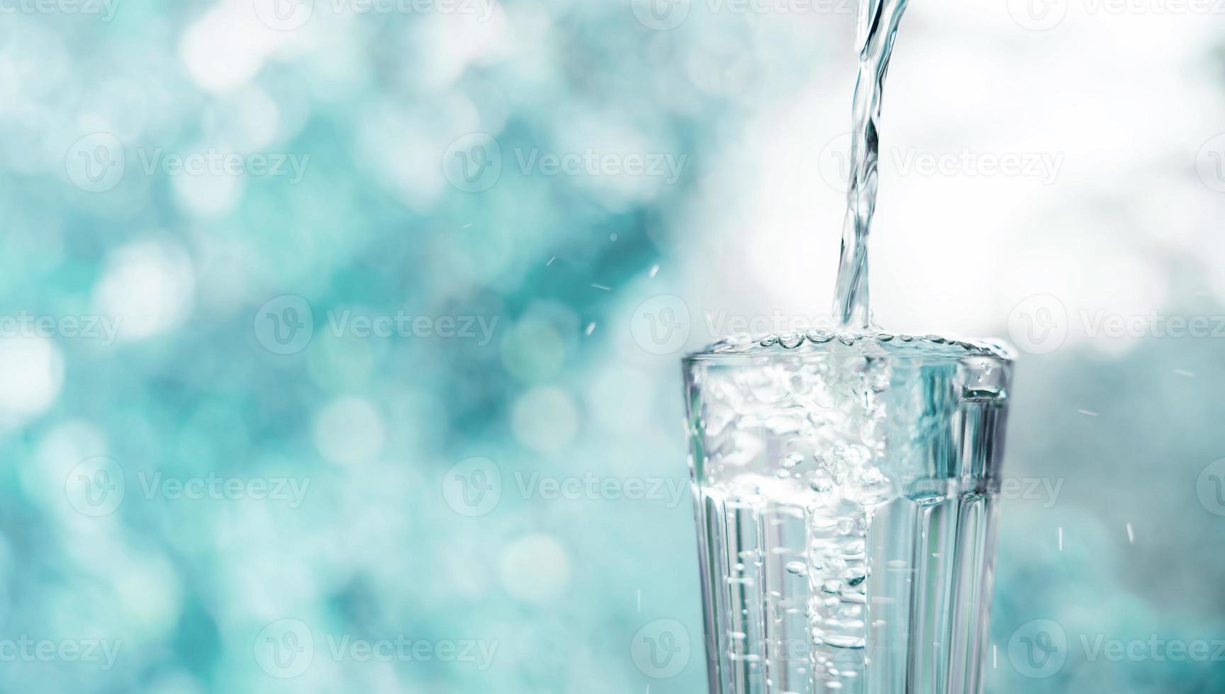 verser de l'eau potable propre dans un verre. arbre nature floue en arrière-plan. tonalité de couleur surréaliste. vue de face. minimal avec vide pour l'espace de copie photo