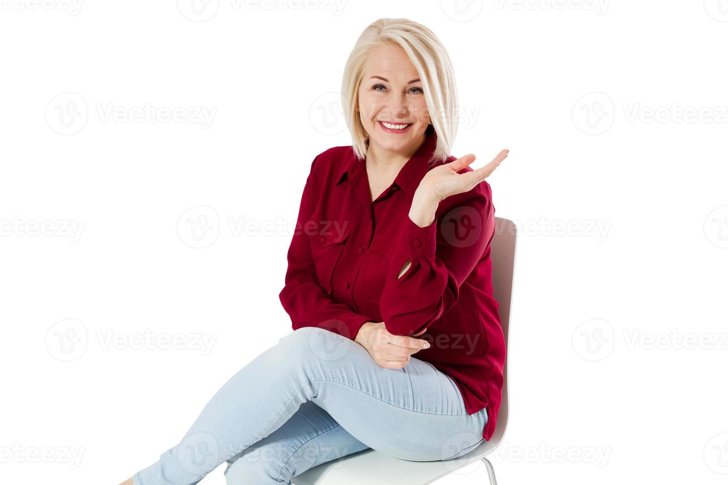 belle femme amicale d'âge moyen assise sur une chaise dans l'espace de copie d'isolement photo