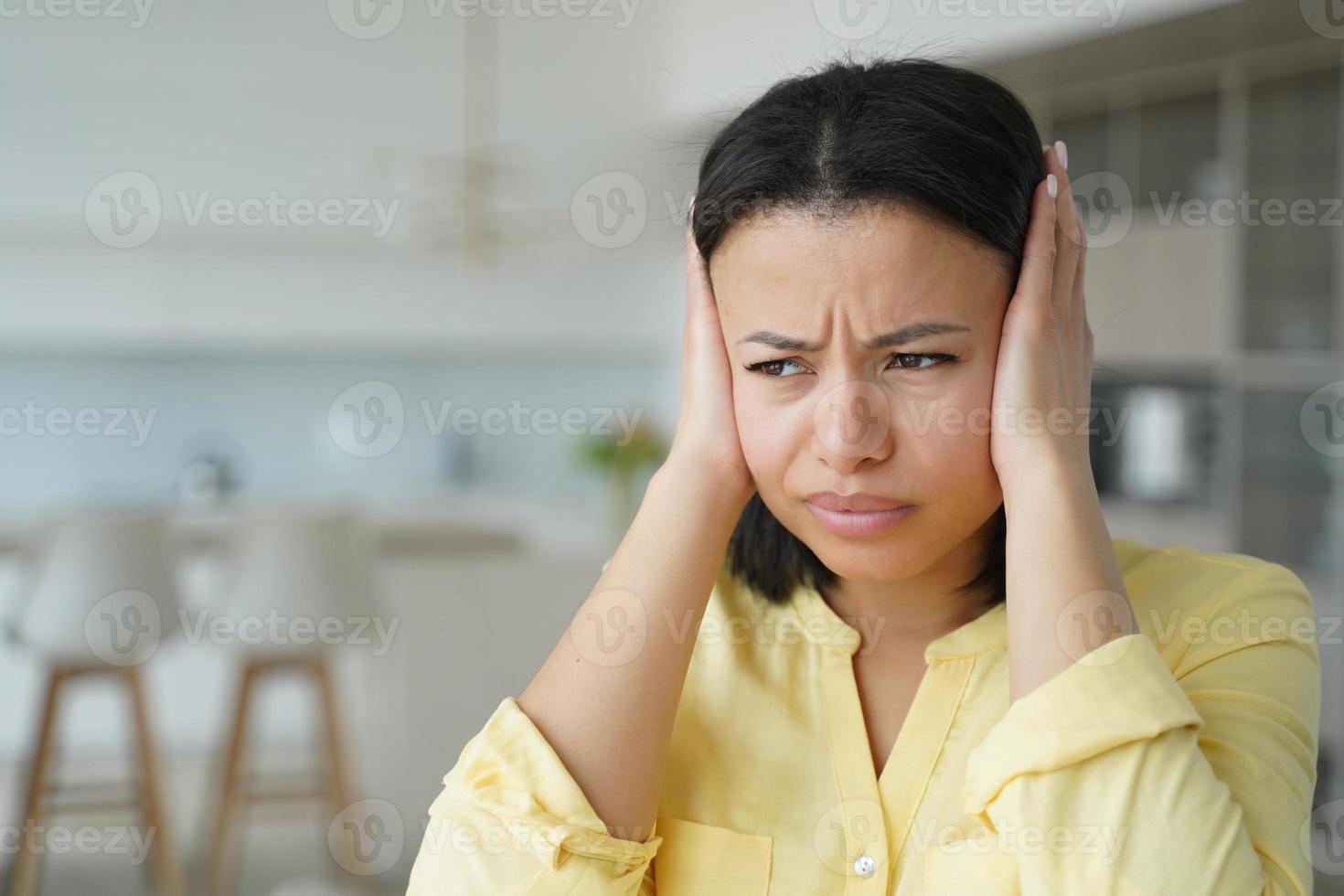 femme nerveuse agacée couvrant les oreilles avec les mains souffrant du bruit fort de l'appartement du voisin photo