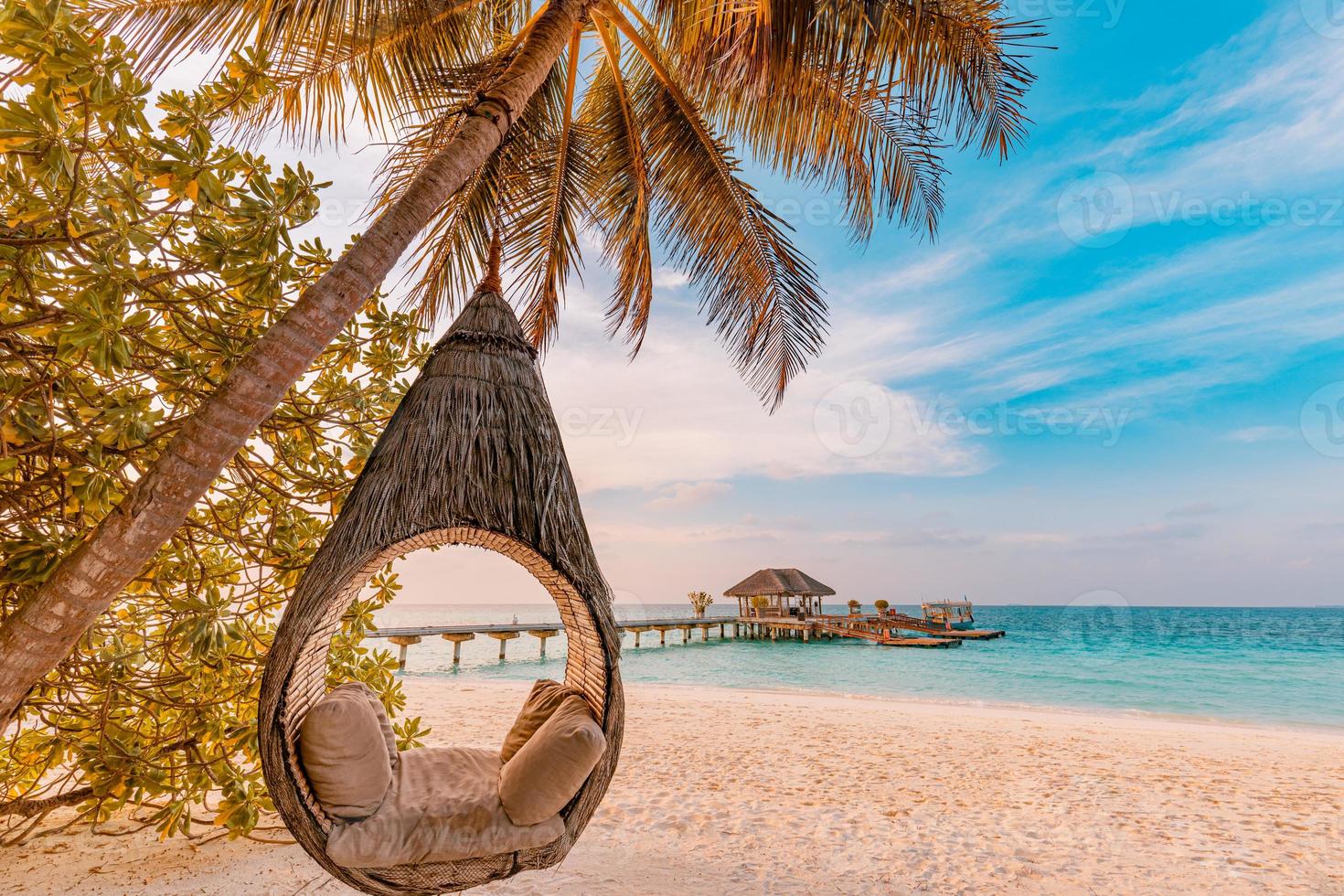 coucher de soleil sur la plage tropicale comme paysage d'été avec hamac de balançoire de palmier de plage de luxe, rivage de sable en bord de mer pour le paysage de plage au coucher du soleil. concept de vacances et de vacances d'été de paysage de plage tranquille photo