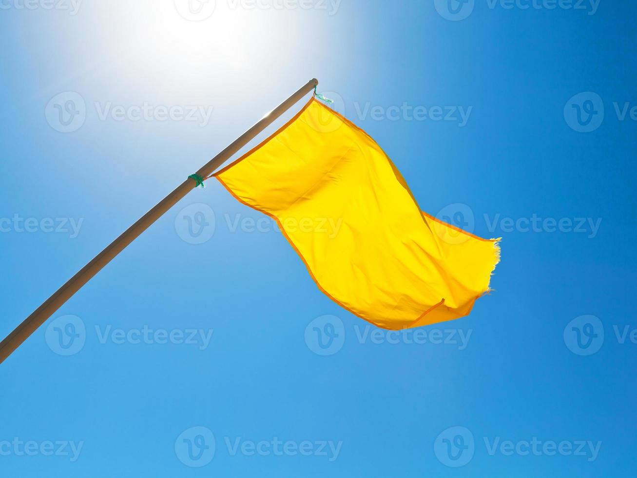 drapeau jaune d'avertissement sous le soleil avec un ciel bleu photo