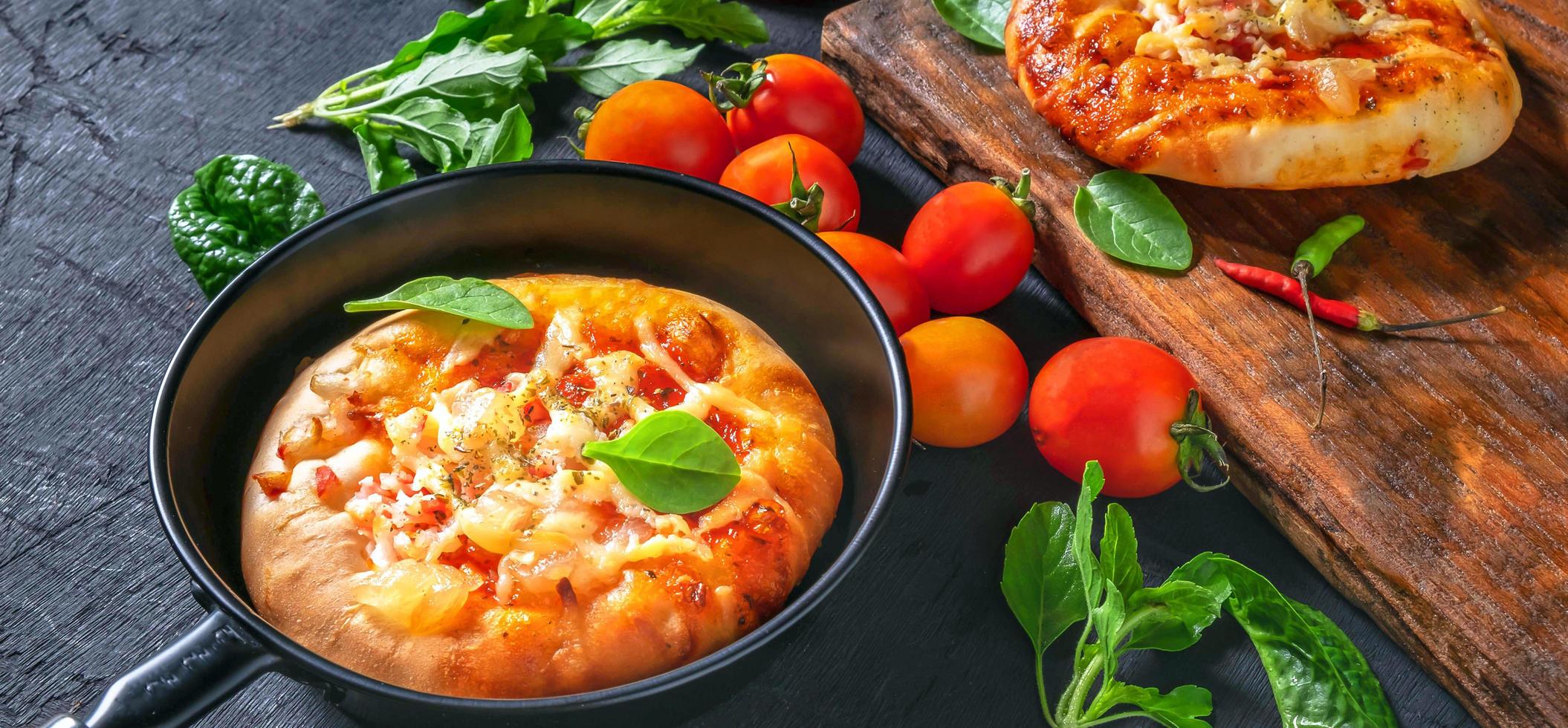 vue de dessus de la pizza faite maison, des légumes, des ingrédients sur un fond en bois noir. la pizza cuit dans la poêle. pizza photo