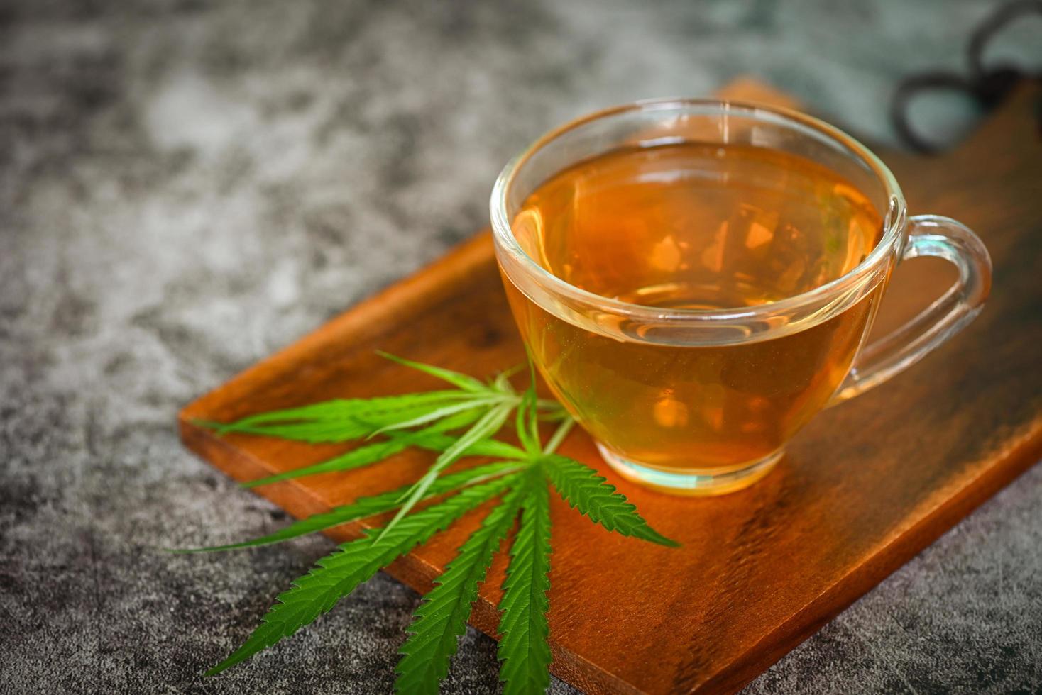 thé de cannabis à base de plantes sur une tasse de thé avec des feuilles de cannabis feuilles de marijuana herbe sur fond de bois, thé de santé avec des feuilles de chanvre plante thc cbd herbes alimentaire et médical photo