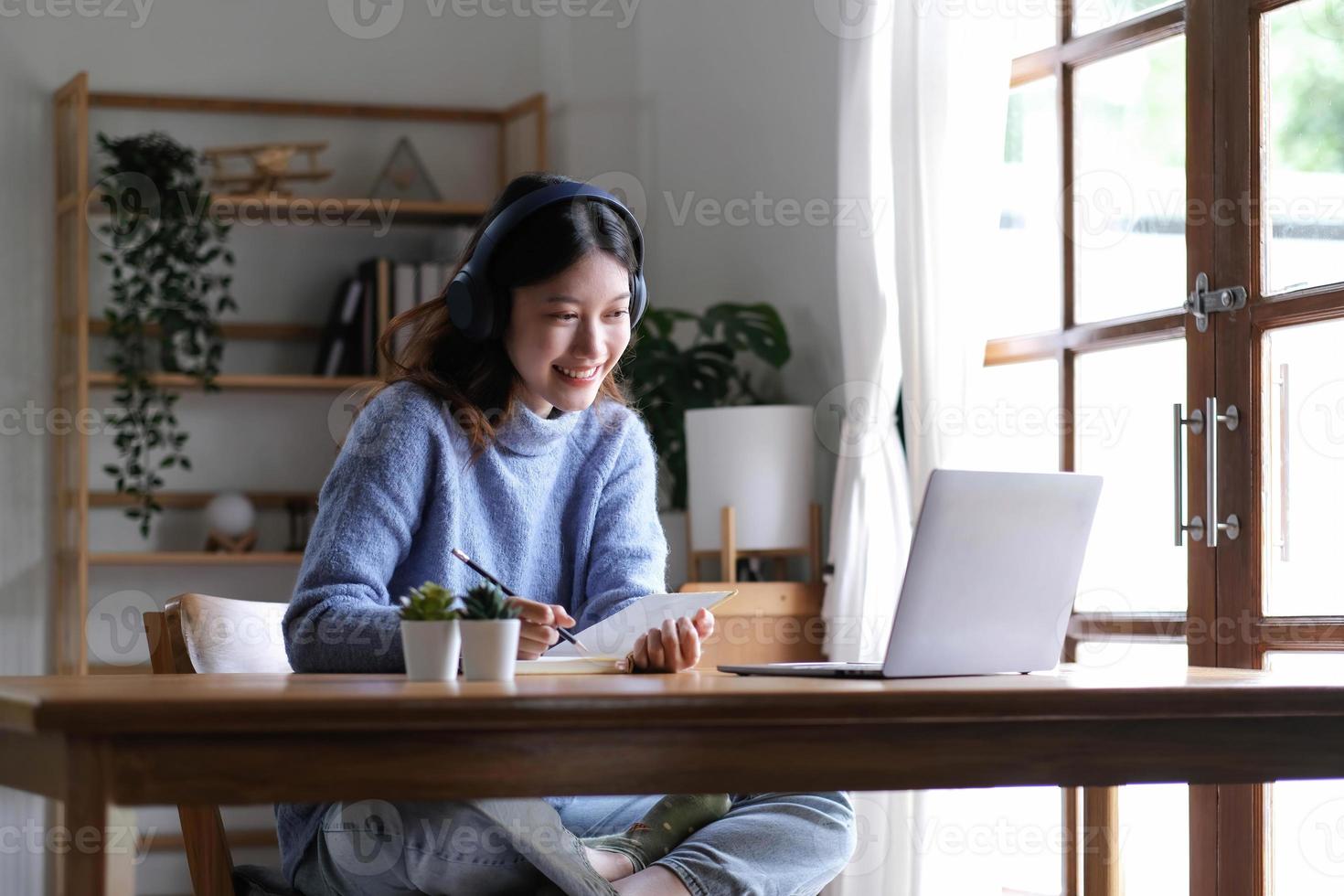 un jeune étudiant universitaire asiatique portant des écouteurs pour étudier en ligne à la maison, pendant la période de l'épidémie de virus et n'a pas fréquenté l'université. photo