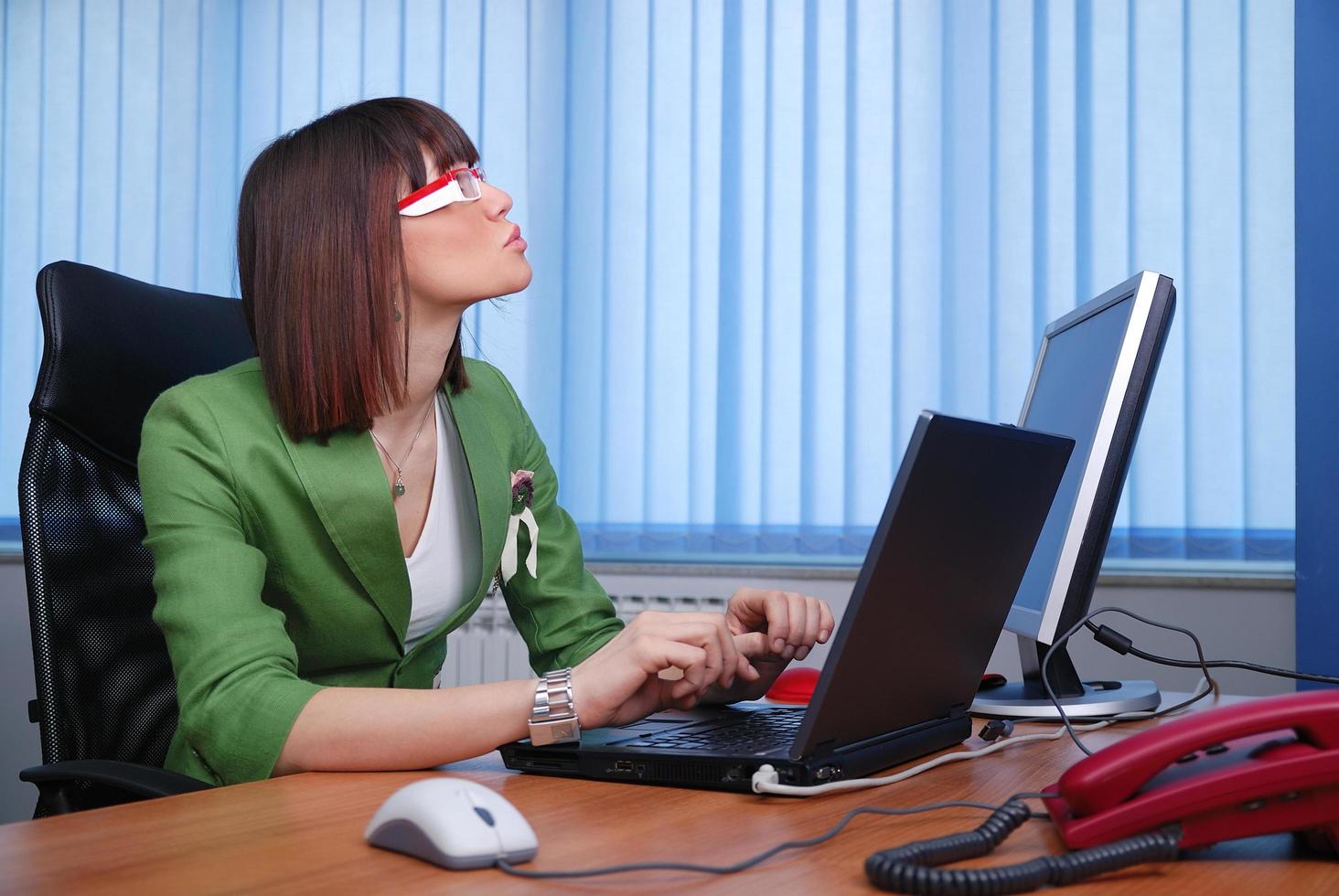 souriante jeune femme d'affaires travaillant sur un ordinateur portable au bureau. photo