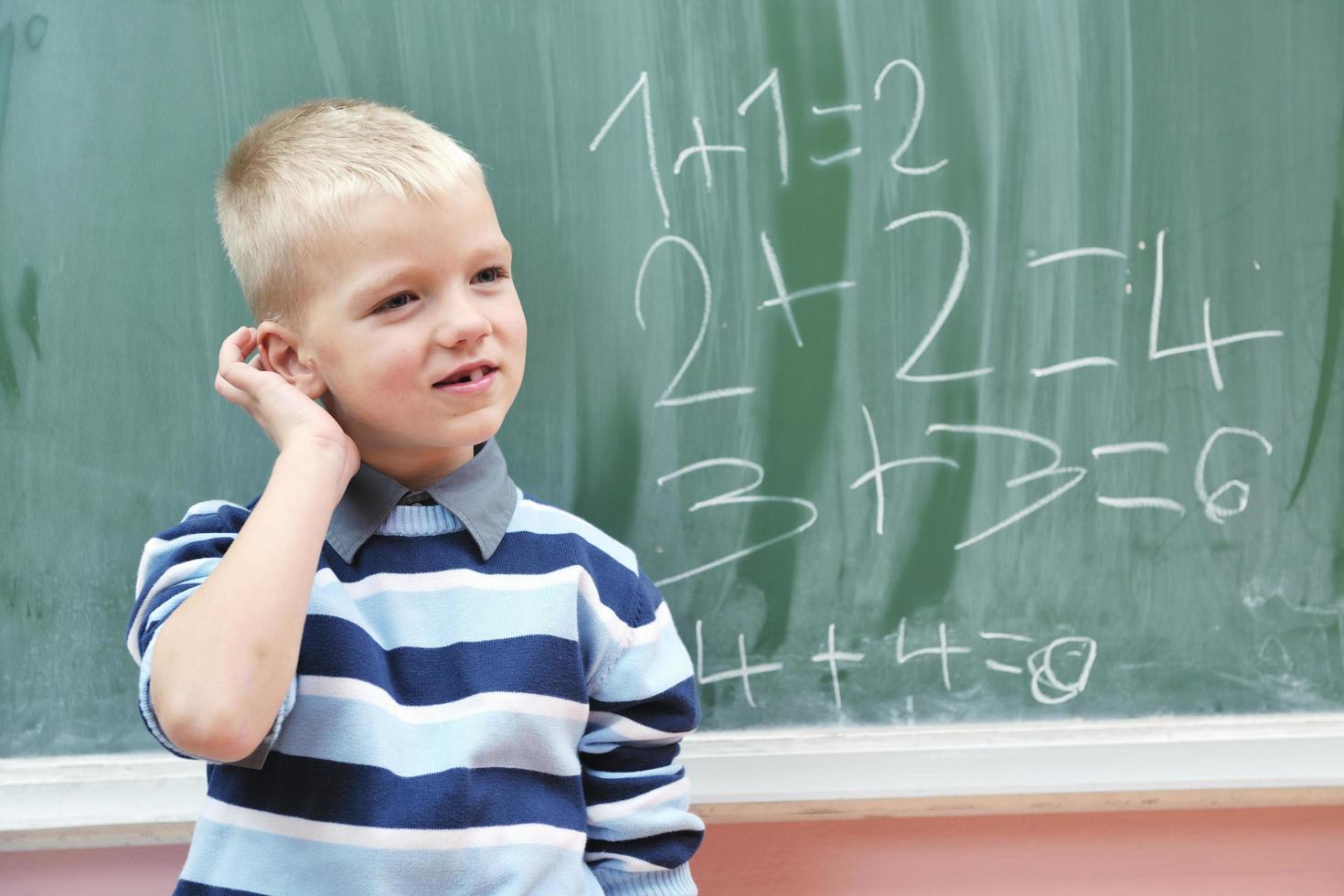 heureux jeune garçon aux cours de mathématiques de première année photo