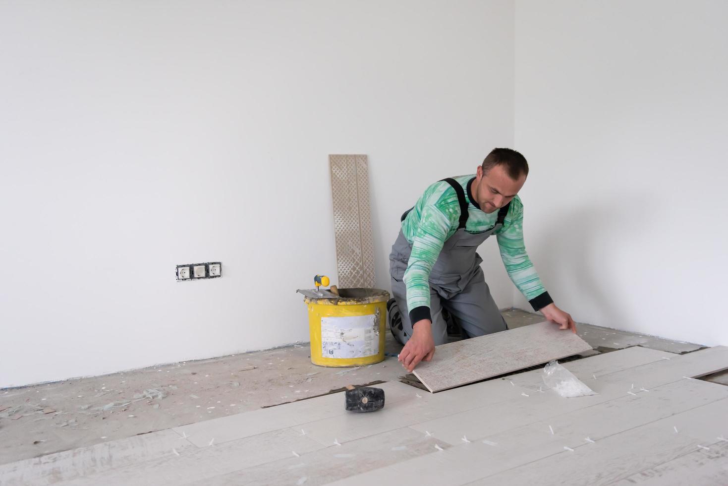 travailleur installant les carreaux en céramique effet bois sur le sol photo