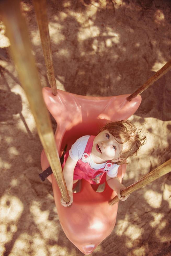 petite fille se balançant sur une aire de jeux photo